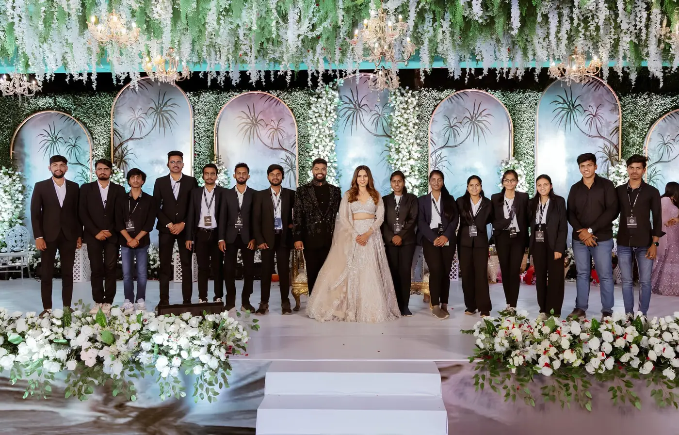 TNP team on a white floral wedding stage with the couple