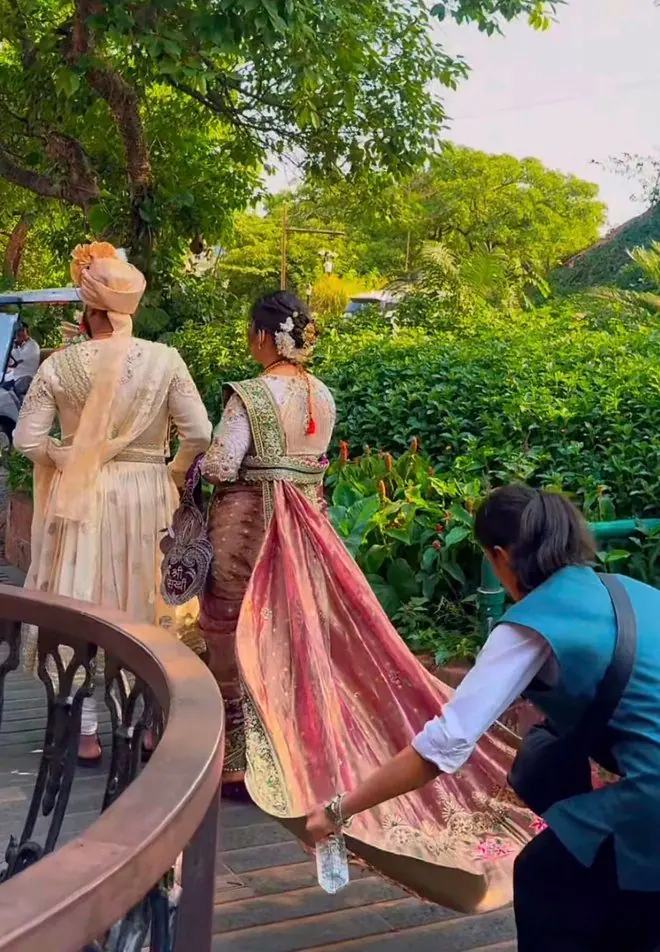 A TNP team member helping with the bride’s outfit as the couple walks to a car